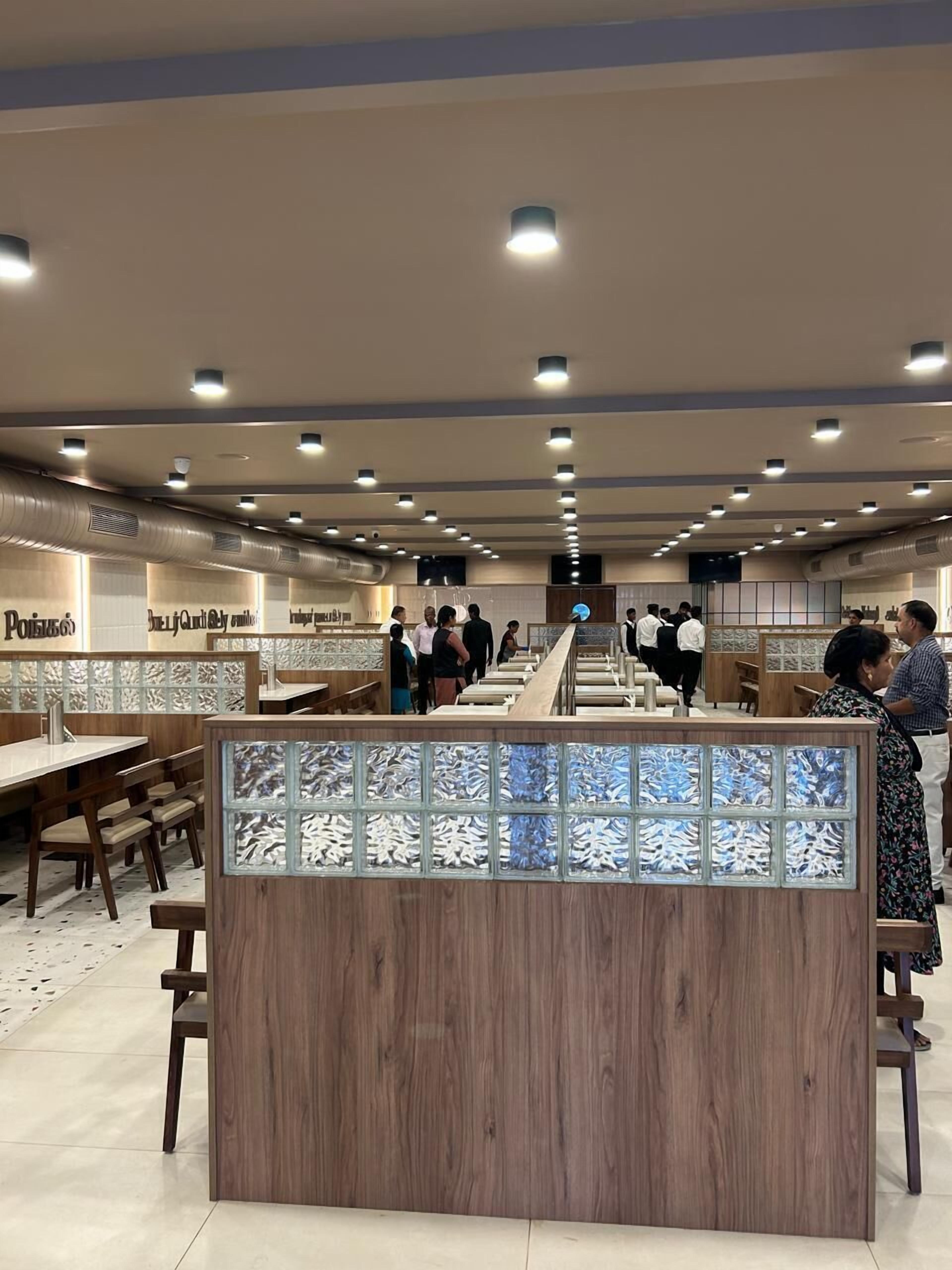 A spacious restaurant with multiple dining areas, wooden furniture, and a central counter.