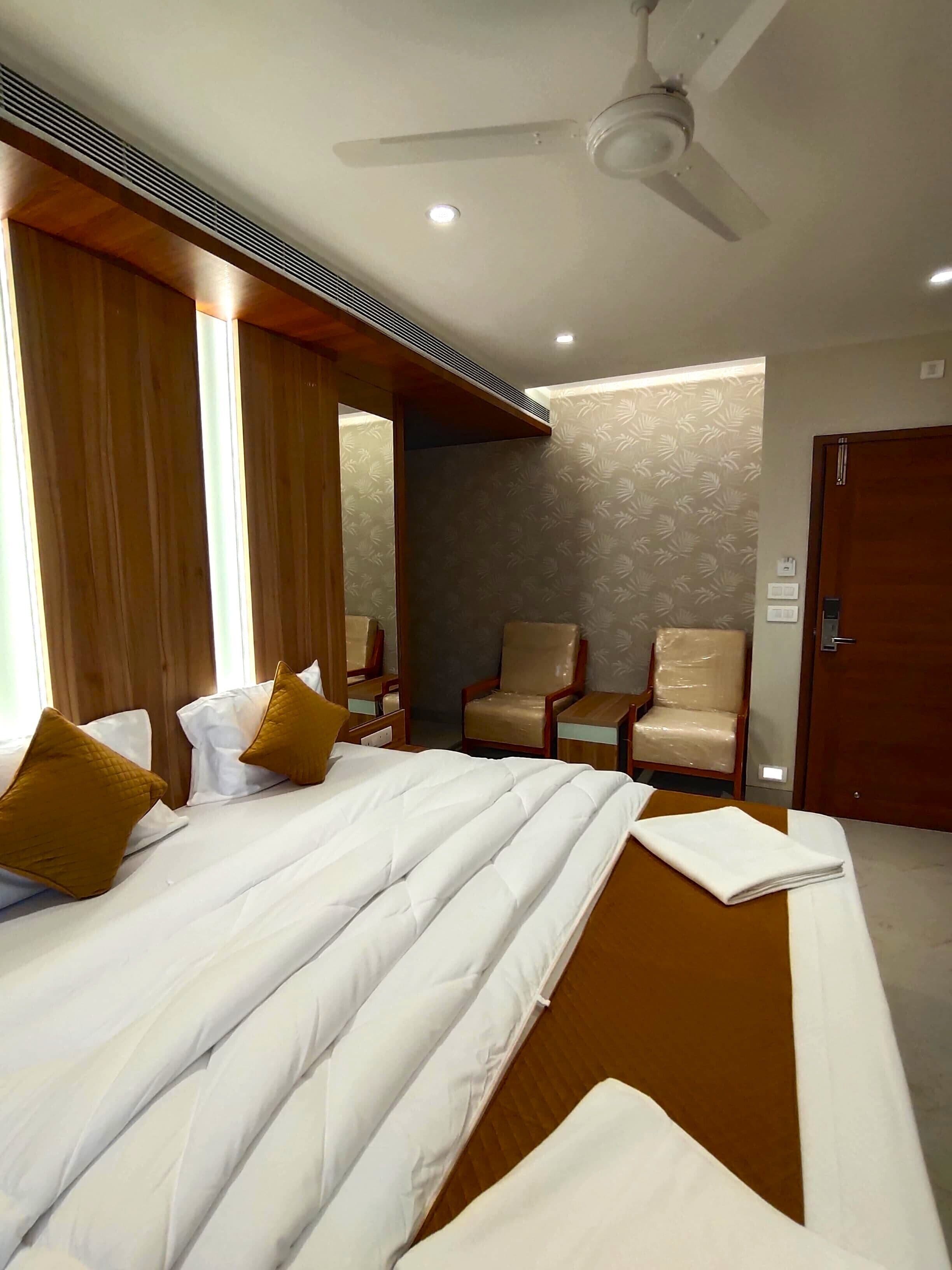 Ein Hotelzimmer mit Bett, zwei Stühlen, einem Deckenventilator und einer Tür.