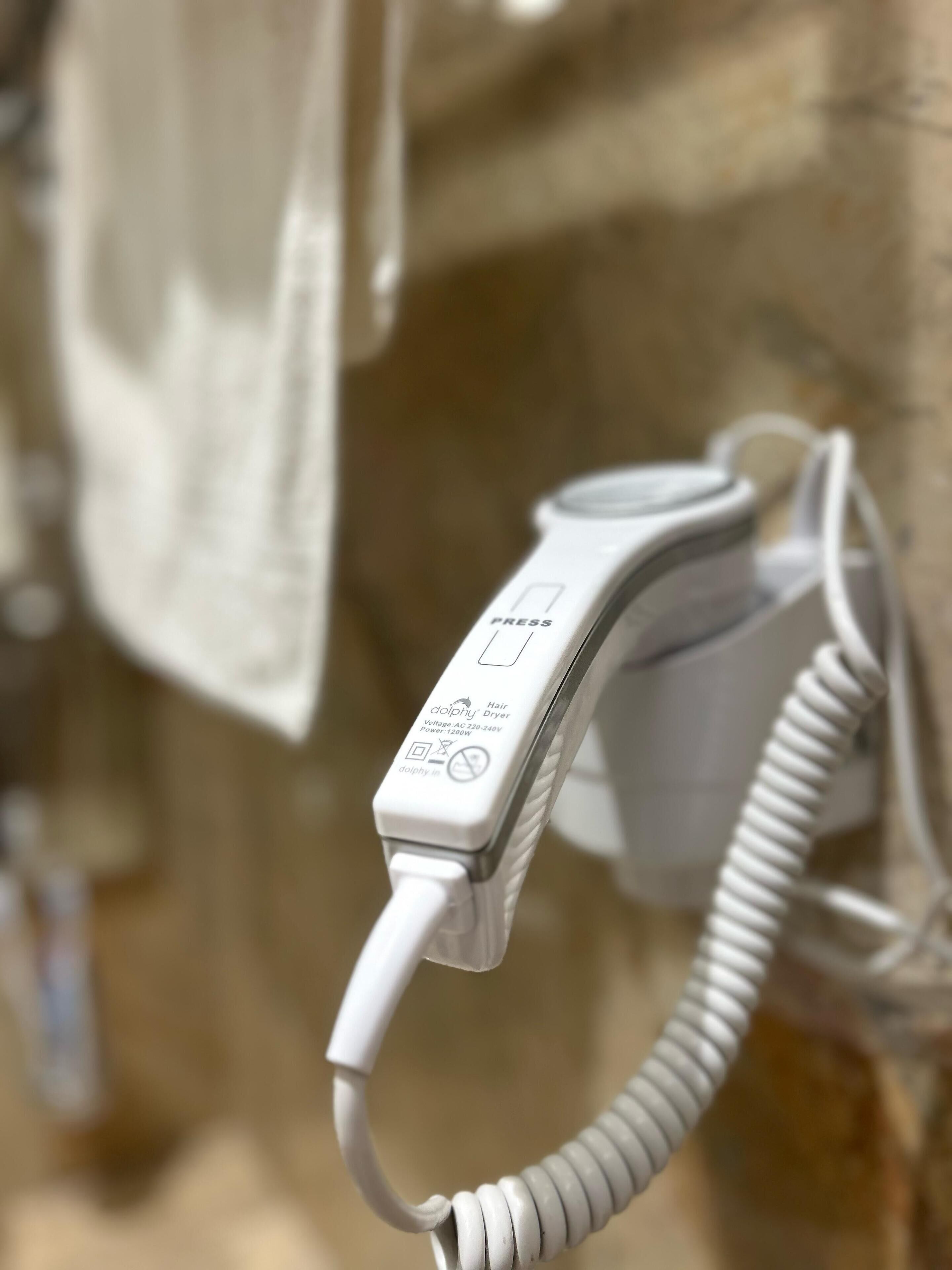 A hair dryer plugged into a wall socket.