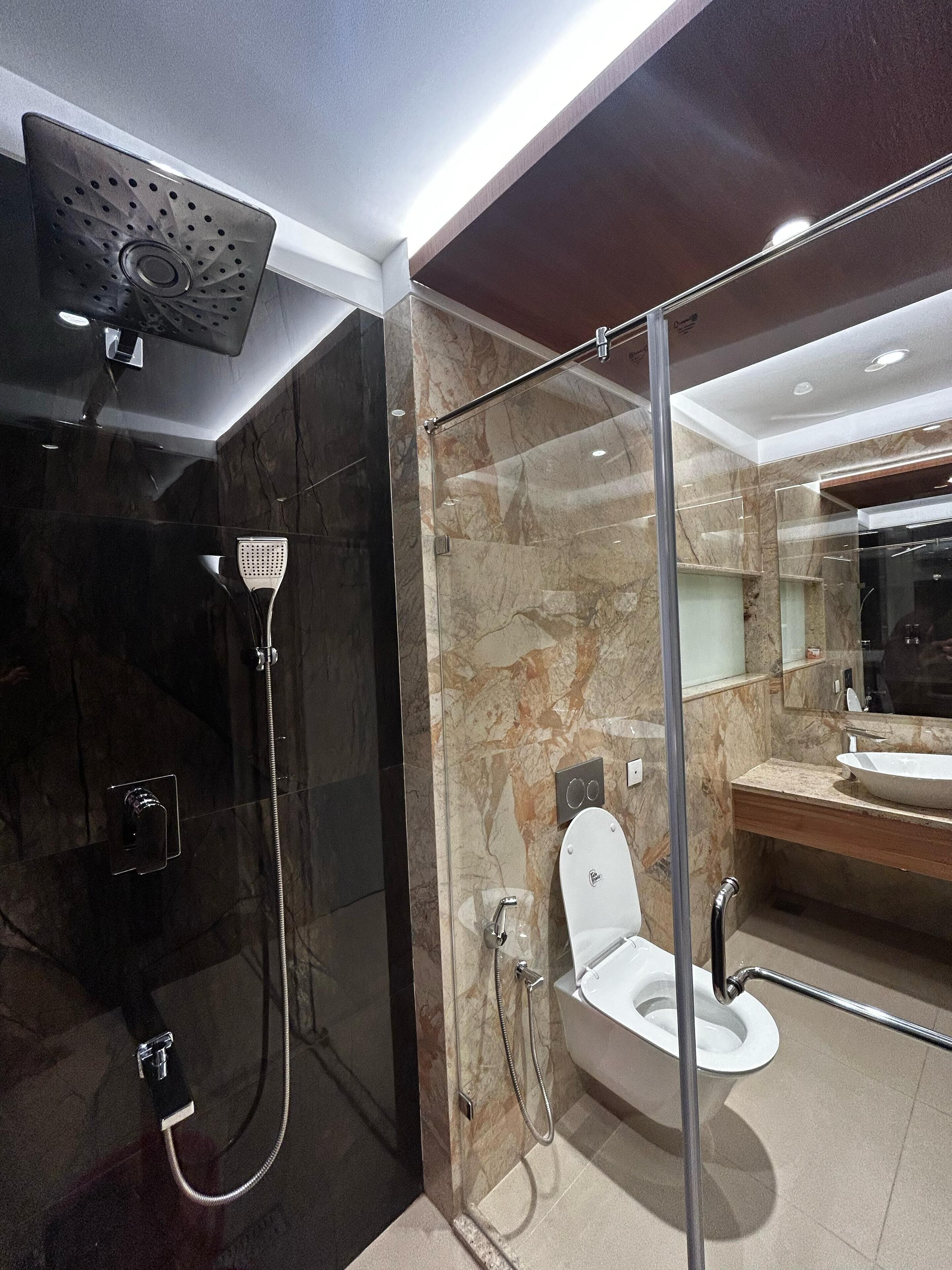 A modern bathroom with a glass-enclosed shower, a separate toilet, and a vanity with a large sink.