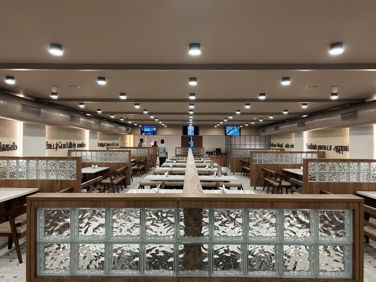 Ein geräumiges Restaurant mit mehreren Tischen und Sitzgelegenheiten, einem zentralen Durchgang und dekorativen Wandverkleidungen.