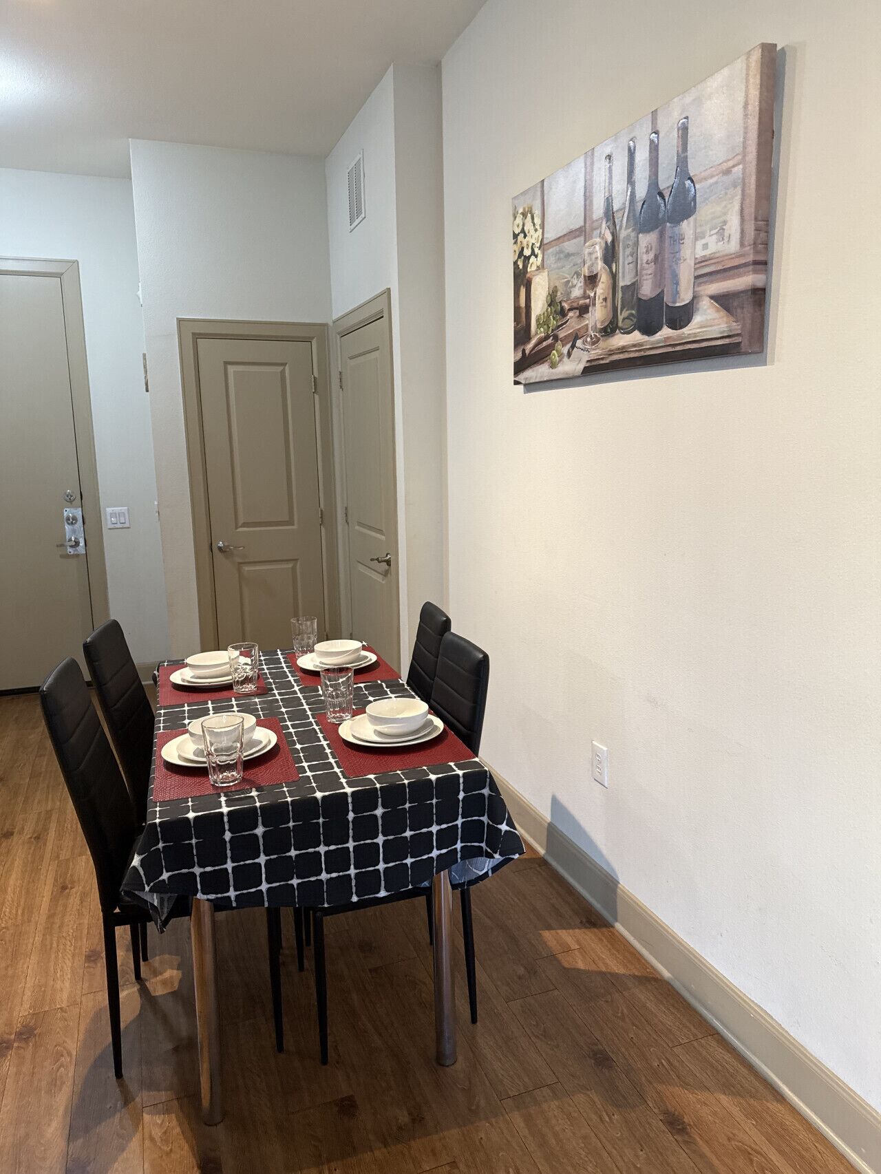 Ein Essbereich mit einem Tisch für vier Personen, Stühlen und einem Bild an der Wand.