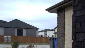 Un quartier résidentiel avec des maisons, une allée et une poubelle bleue.