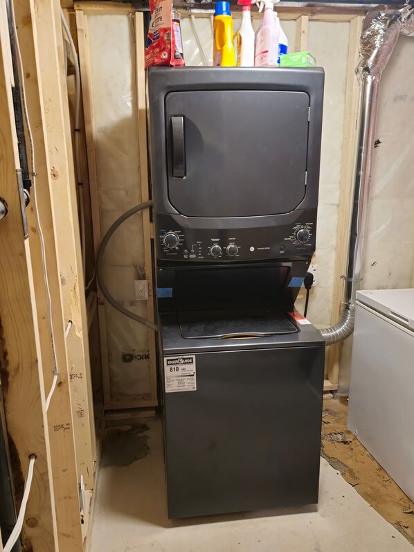A compact washer and dryer unit with a control panel, placed in a wooden utility room.