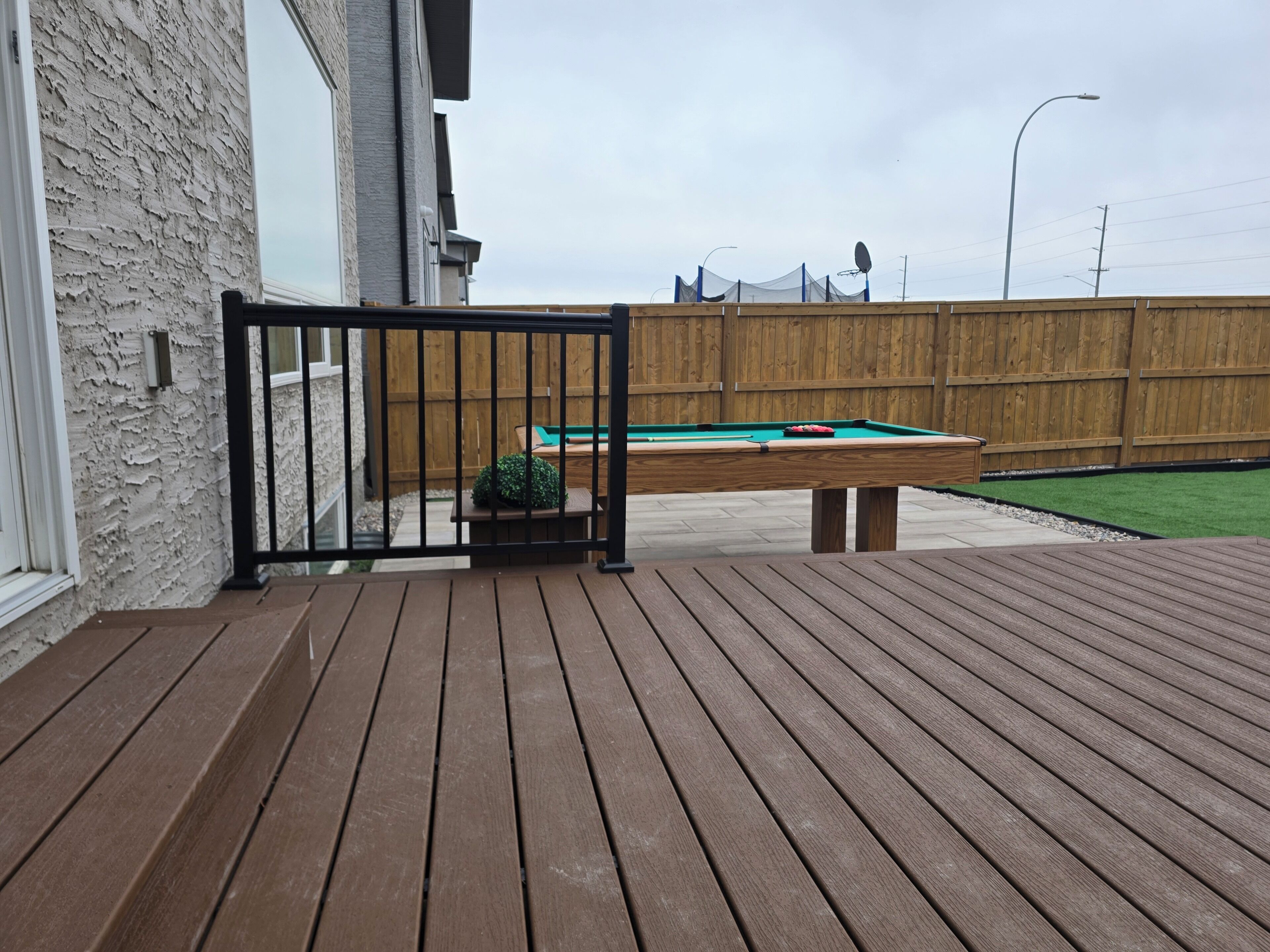 Eine Holzterrasse mit Billardtisch und einem grünen Rasen.