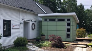 A white building with a green extension, a wreath on the door, and a gravel pathway leading to the entrance. - Cozy In Town Manchester Studio w/ Loft Bedroom. (Manchester)