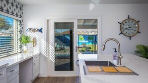 A modern kitchen with a sink, a clock, and a view of the outside. - Life can be a Beach (Gilbert)