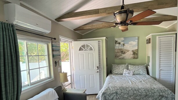 A bedroom with a bed, a sofa, a ceiling fan, and a door. - Charming studio with large outdoor patio.  Fully fenced and pets are welcome! (St. Petersburg)
