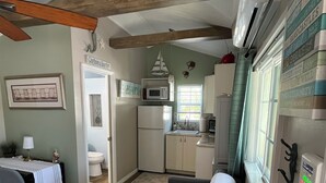 A compact living space with a kitchenette, a dining area, and a sofa. - Charming studio with large outdoor patio.  Fully fenced and pets are welcome! (St. Petersburg)