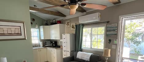 A cozy room with a bed, a desk, a sofa, and a kitchenette.