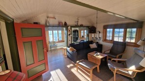A cozy living room with a sofa, chairs, and a small table. There is a door leading to another room. - Cozy cabin with a spectacular view! Pet-friendly - 15 minutes to skiing resort! (Buskerud)