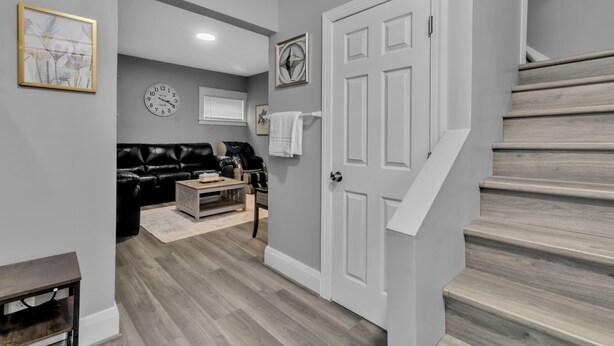 A modern living room with a grey couch, a coffee table, and a fireplace. There is a staircase leading to another level.