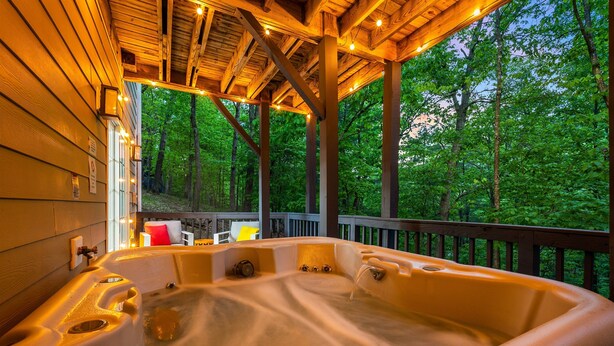 Un jacuzzi con terraza de madera y vistas a un bosque.
