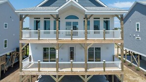 A two-story house with a balcony on the ground floor and a covered porch on the upper floor.