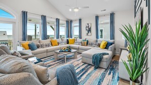 A spacious living room with a large sectional sofa, a coffee table, and a view of the ocean.