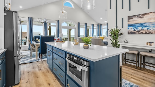 A modern kitchen with a central island, built-in appliances, and a dining area with a view.