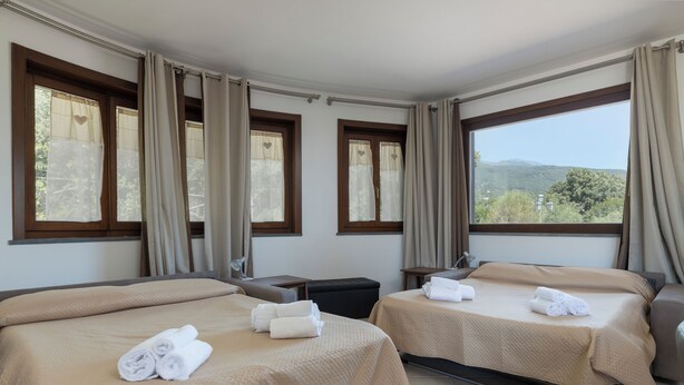 Habitación de hotel con dos camas, un escritorio y vistas al exterior.