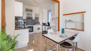 Una cocina moderna con armarios blancos, un comedor con mesa y sillas, y un ventilador de techo.