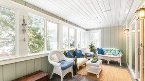 A sunroom with wicker furniture, large windows, and a wooden bench. - FAMILY-FRIENDLY, King Bed, Outdoor Space, Pet-Welcome - Intervale Lodge (Intervale)