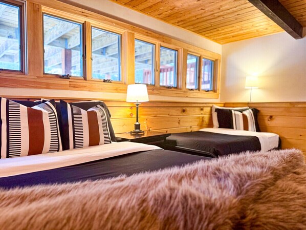 Una habitación acogedora con cama, mesita de noche, lámpara y ventana con vistas al exterior.