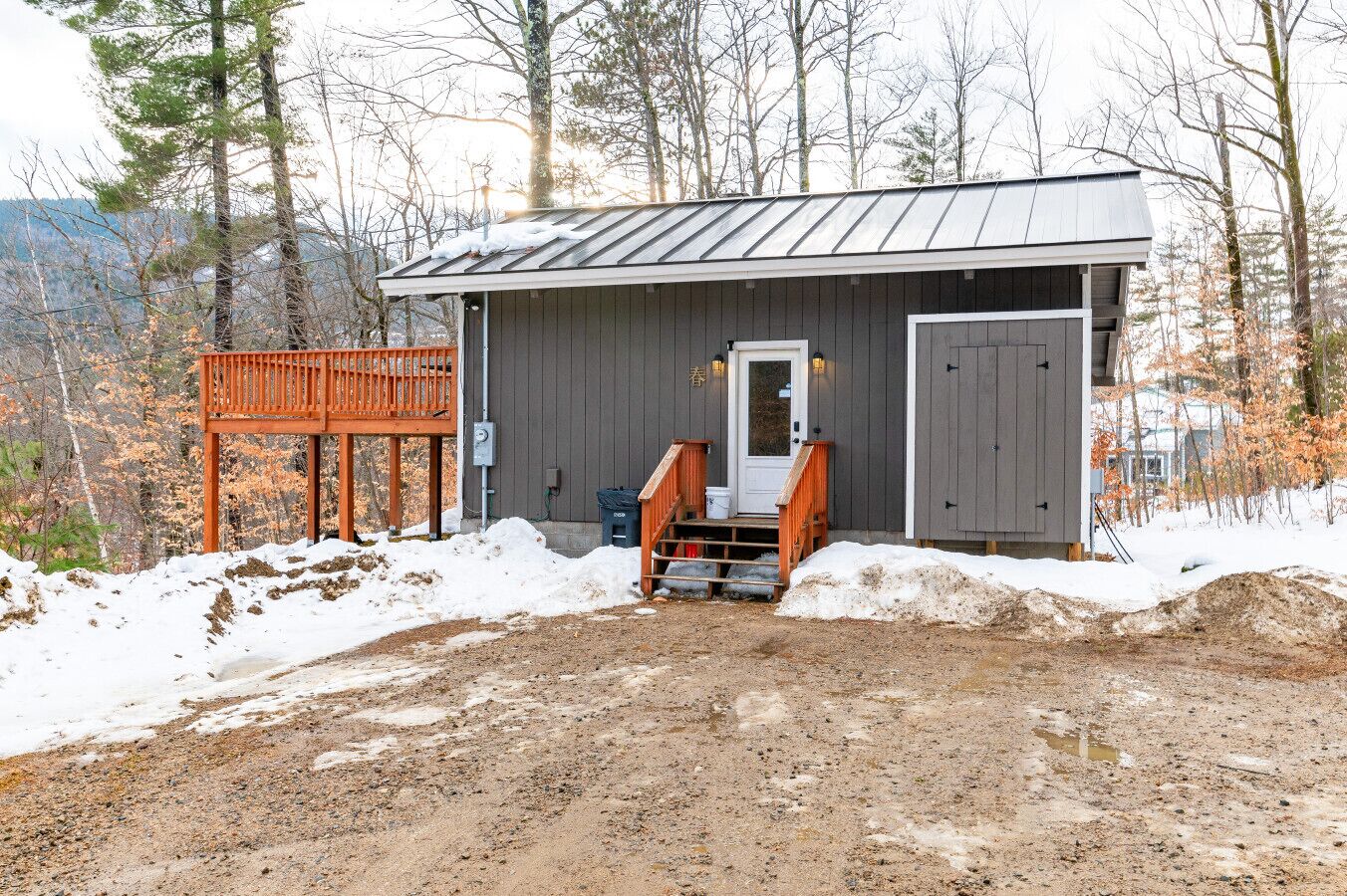 Eine rustikale Holzhütte mit Metalldach, einer Holzterrasse und einer kleinen Veranda.
