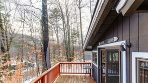 A wooden deck with a glass door leading to a room, surrounded by trees and a snowy landscape. - Bring the dog-colorful SacoRiver (Bartlett)