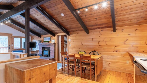 A wooden interior with a dining table and chairs, a fireplace, and a television. - Bring the dog-colorful SacoRiver (Bartlett)