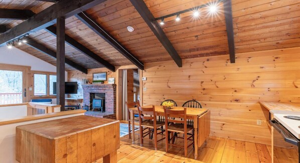 A wooden interior with a dining table and chairs, a fireplace, and a television. - Bring the dog-colorful SacoRiver (Bartlett)