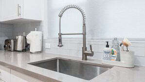 A modern kitchen with a stainless steel sink, a kettle, a toaster, and a soap dispenser. - Renovated Midtown Home, Walkers Dream  to Food/Fun (Reno)