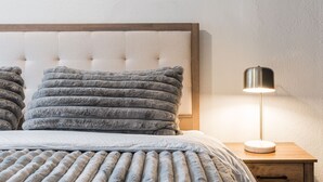 A neatly made bed with grey fluffy pillows and a grey striped blanket. There is a bedside table with a lamp and a drawer. - Renovated Midtown Home, Walkers Dream  to Food/Fun (Reno)