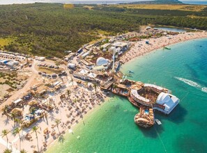 Luftaufnahme eines Küstenresorts mit Strand, einer Marina und einer großen Kuppelstruktur.
