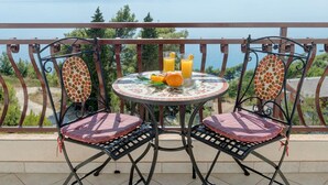 A balcony with a table and two chairs, overlooking a scenic view of a lake and mountains. - Apartments Tafra - One Bedroom Apartment (Lokva Rogoznica)