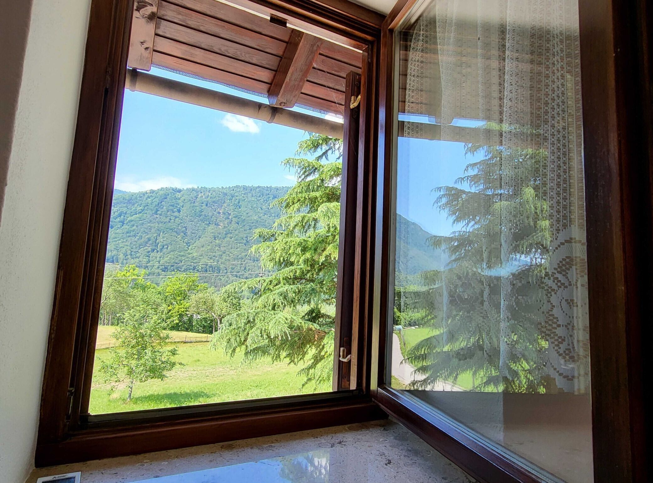 A room with a large window offering a view of a green landscape and trees.