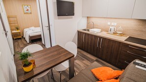 Camera d'albergo compatta con angolo cottura, zona pranzo e un letto.