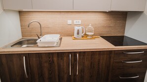 Una cucina compatta con lavello, bollitore e tostapane sul piano di lavoro.