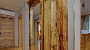 A hallway with wooden flooring, a mirrored wardrobe, and a door with a handle.