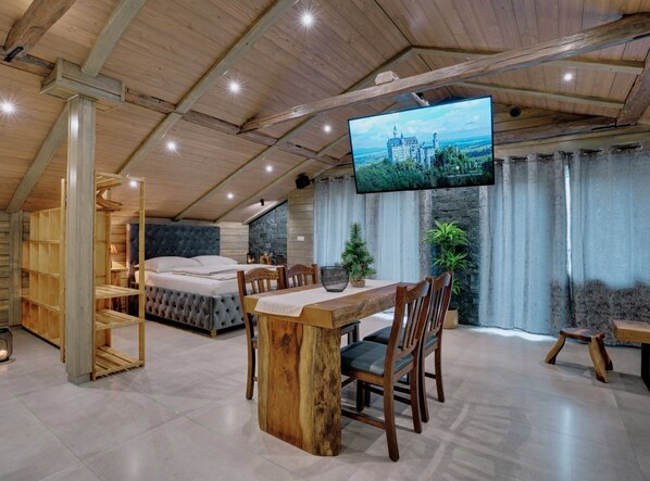 A cozy room with a bed, wooden furniture, a TV, and a stone wall.
