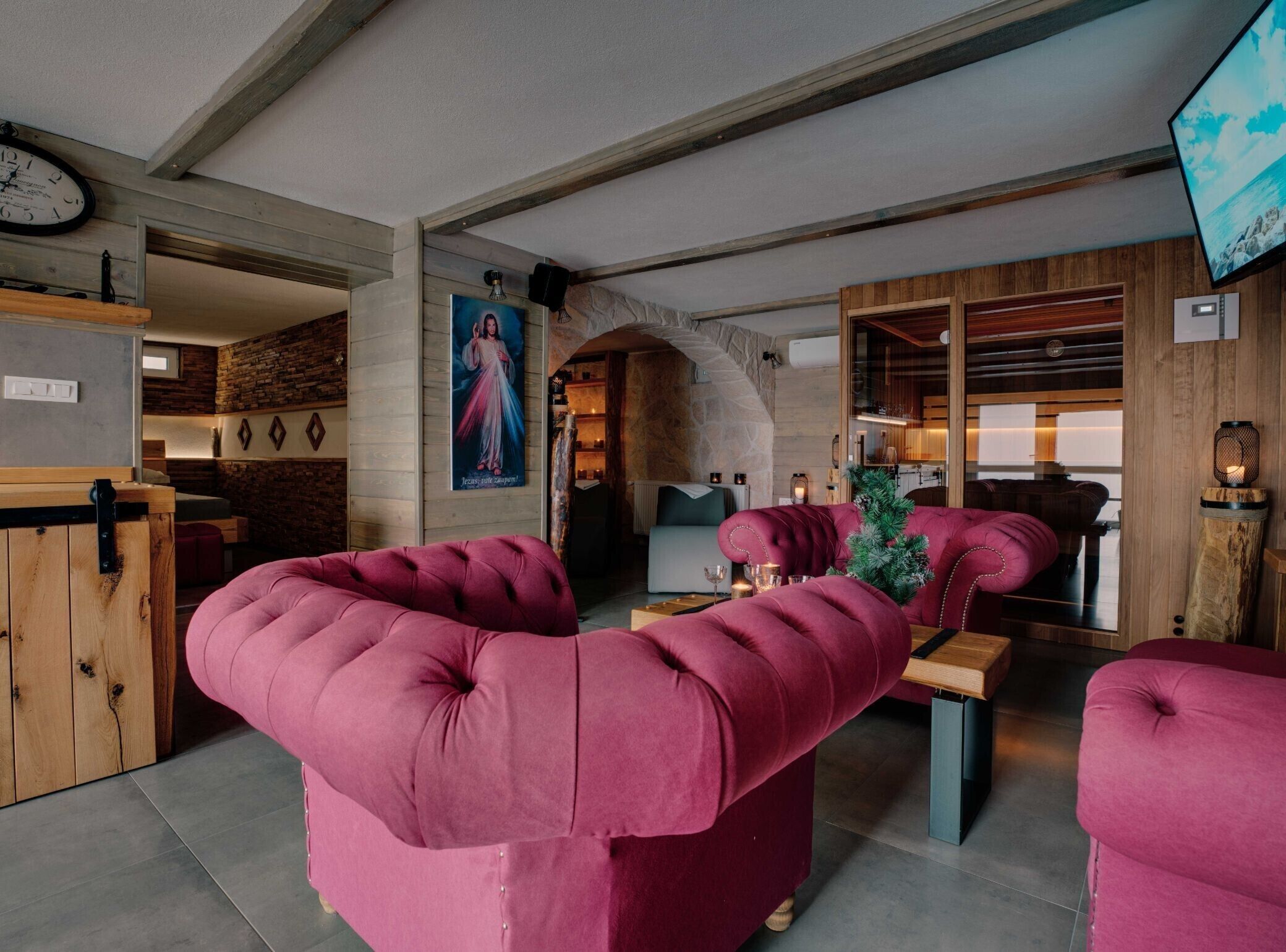 Un intérieur chaleureux avec des fauteuils rouges moelleux, un comptoir d’accueil en bois et un mur en pierre.
