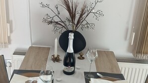 Une table à manger dressée avec une bouteille de vin, deux verres et une bougie.
