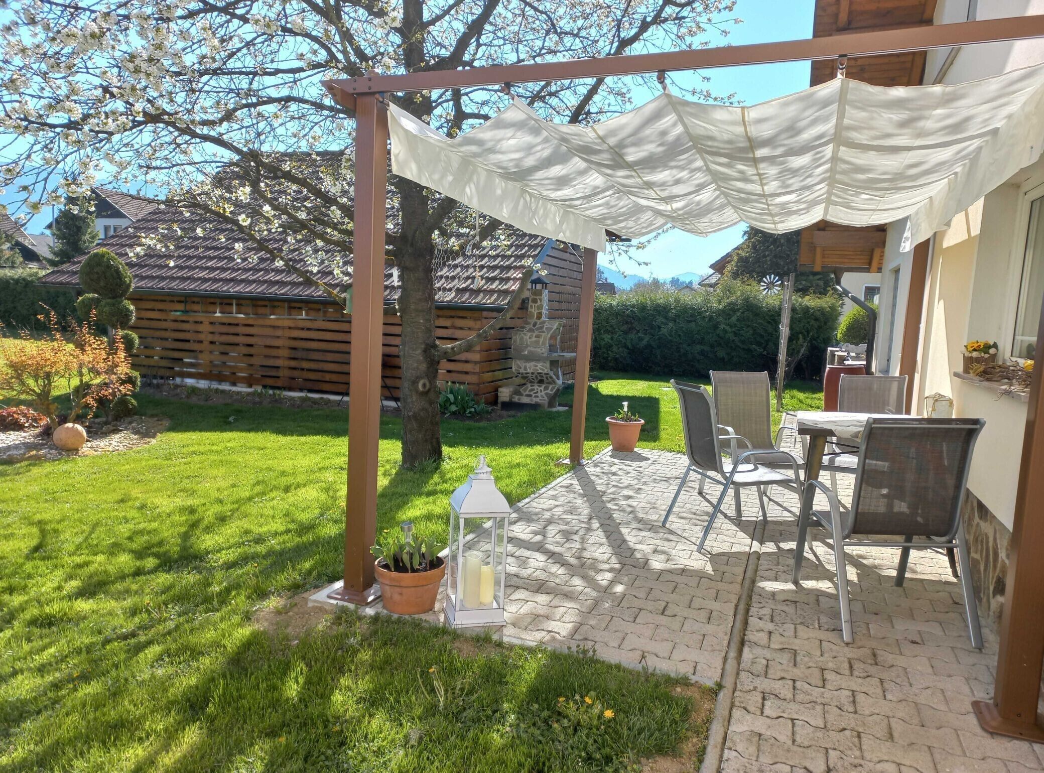Un patio con pérgola, mobiliario exterior y jardín.