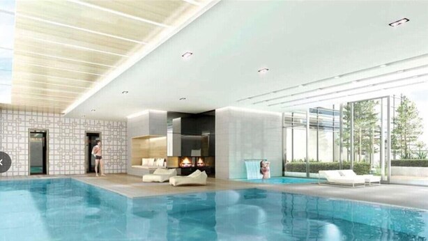 An indoor swimming pool with a modern design, a seating area, and a view of the outdoors.