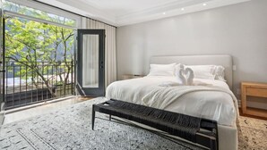 A modern bedroom with a large bed, a bench, a nightstand, and a view of trees through a sliding door. - Luxury Home Yorkville 4bed4bath Backyard Parking (Toronto)