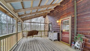 A wooden cabin with a covered porch, a rocking chair, a small white dresser, and a door with a window. - Family-Friendly Tyrone Cabin w/ Deck Near Hiking (Tyrone)