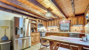 A modern kitchen with wooden cabinets, stainless steel appliances, and a wooden dining table. - Family-Friendly Tyrone Cabin w/ Deck Near Hiking (Tyrone)
