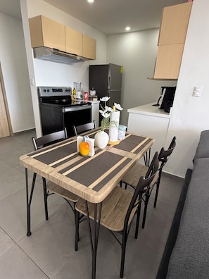 A modern kitchen with a dining area, featuring a central island, chairs, and a table with a woven table runner. - Apartment Escalon. 3 beds & 2 Sofa beds, WIFI, 2 car parking, AC in all bedrooms (San Salvador)