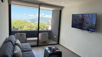 A modern living room with a sofa set, a coffee table, and a television mounted on the wall.