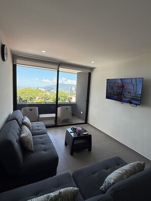 Una sala de estar moderna con un juego de sofá, una mesa de centro y un televisor montado en la pared.