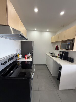Cozinha moderna com fogão preto, armários brancos e micro-ondas.