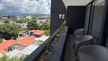 A balcony with a view of a cityscape, including buildings and a mountain.