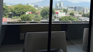 Ein Balkon mit Blick auf eine Stadtlandschaft, inklusive Gebäude und Grünflächen.